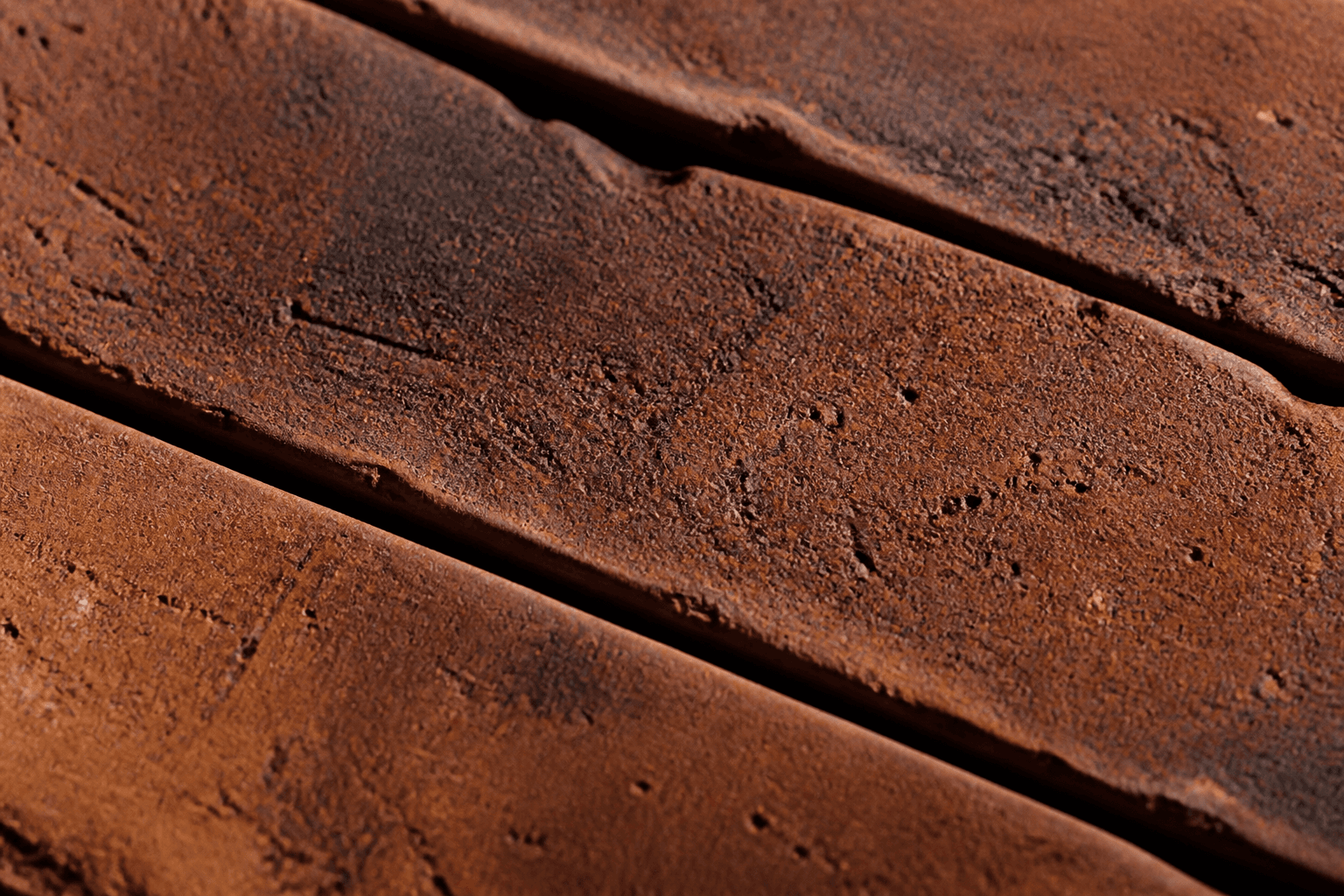 Oversized close-up of kiln-fired brick surfaces, edges and tonal variation